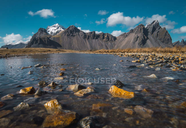 Kalter Kristallstrom zwischen Felsen und felsigen Bergen im Hintergrund, Island — Stockfoto
