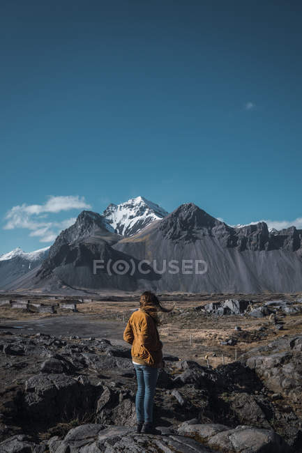 Mujer con el pelo volador de pie en montañas remotas - foto de stock