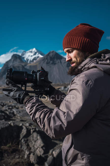 Bärtiger Mann mit professioneller Kamera im Sonnenlicht der Berge — Stockfoto
