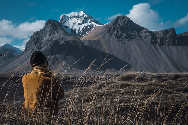 Donna seduta a terra a guardare montagne remote, Islanda — Foto stock