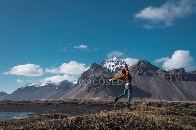 Ragazza eccitata che salta sulla costa con le montagne sullo sfondo, Islanda — Foto stock