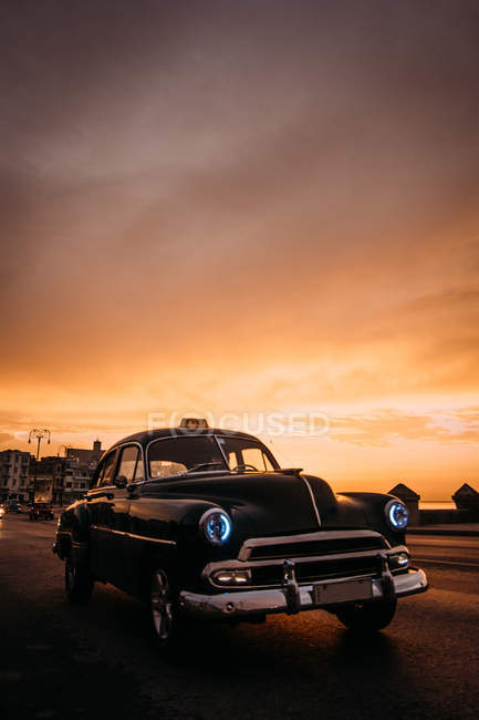 Vintage coche de conducción por carretera en la puesta del sol - foto de stock