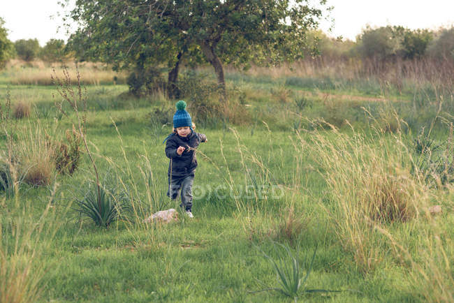 Menino correndo no parque ensolarado — Fotografia de Stock
