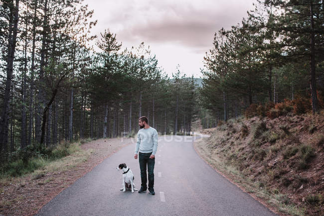 Man with dog standing on road — Stock Photo