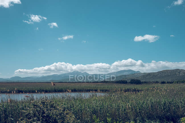 Incroyable vue paysage pittoresque des montagnes ciel bleu nuages et lac avec herbe haute — Photo de stock