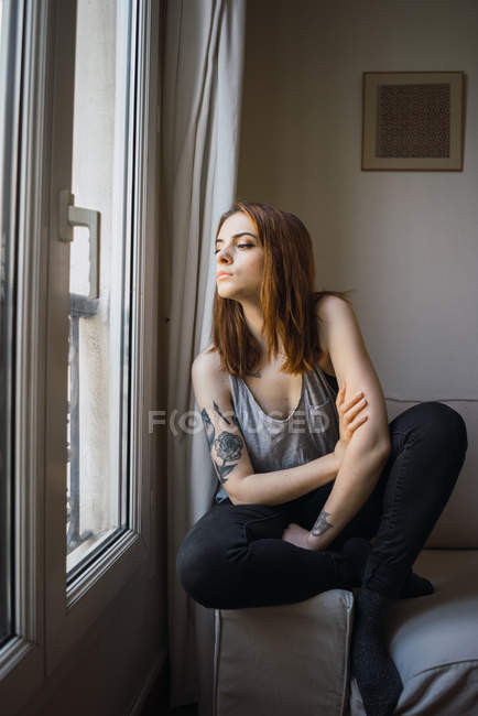Татуйована жінка сидить у вікні — стокове фото