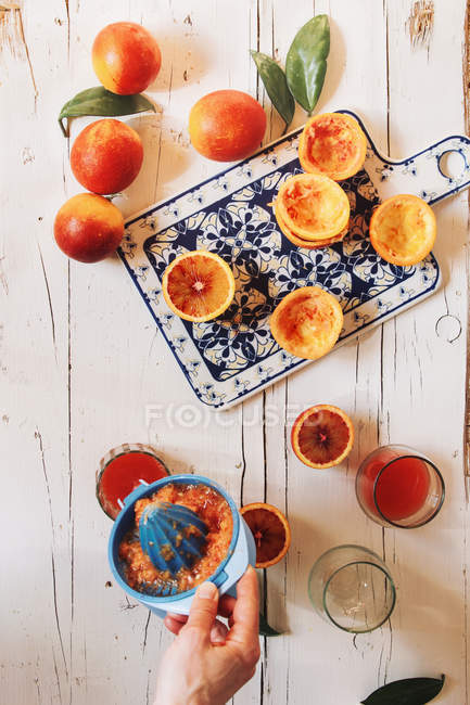 Hand squeezing blood orange juice — Stock Photo