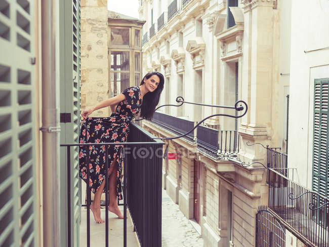 Donna in piedi sul balcone in città — Foto stock