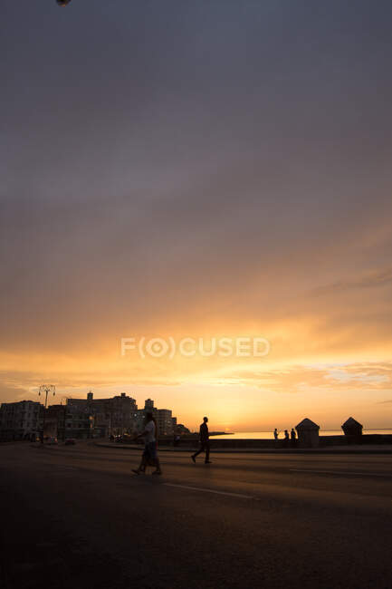 Veduta della gente sul lungomare con l'oceano nel tramonto colorato sullo sfondo, città di Cuba. — Foto stock