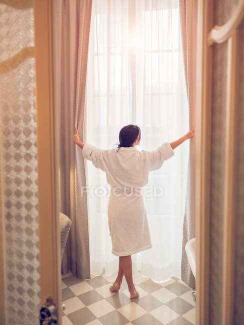 Mulher de roupão de banho na janela — Fotografia de Stock