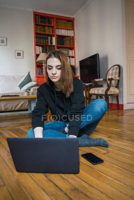 Mujer escribiendo en el portátil en el suelo - foto de stock