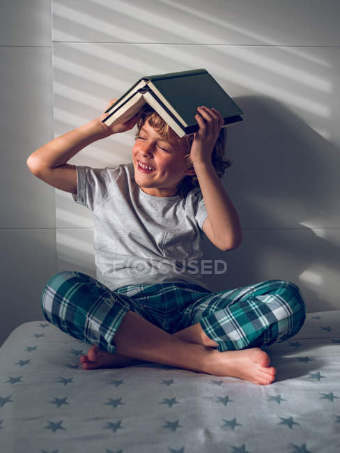 Ragazzo con libri sopra la testa — Foto stock