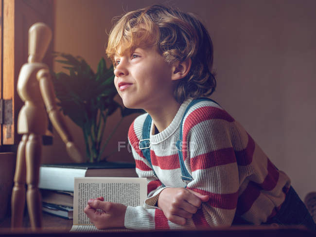 Хлопчик сидить з книгою за столом — стокове фото