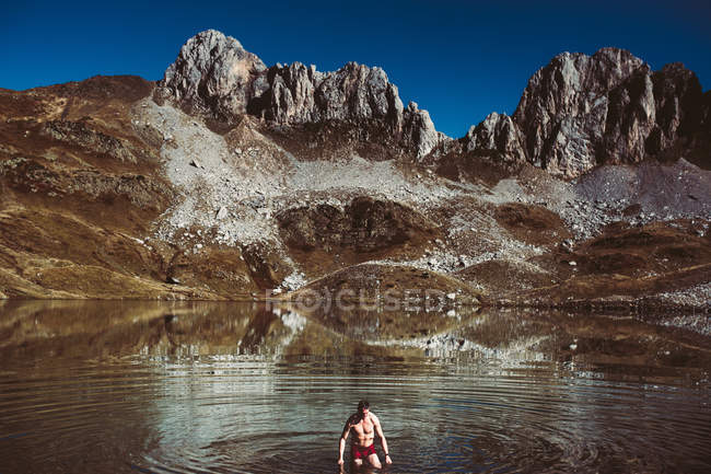 Hombre caminando fuera de lago de montaña - foto de stock