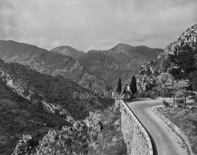 Black and white shot of road running on slope of rocky mountain range in sunlight, Belgium. — Stock Photo