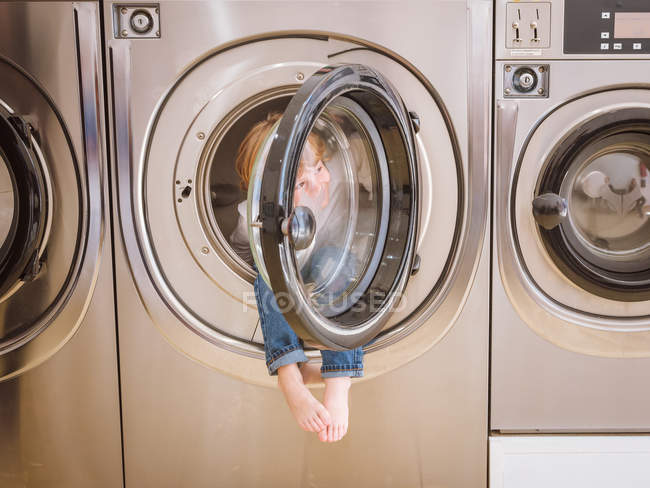 Curious boy sitting inside washing machine in laundry. — Stock Photo