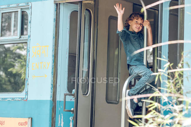 Menino sentado no corrimão do trem — Fotografia de Stock