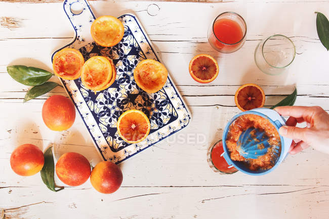 Mano exprimiendo jugo de naranja de sangre - foto de stock