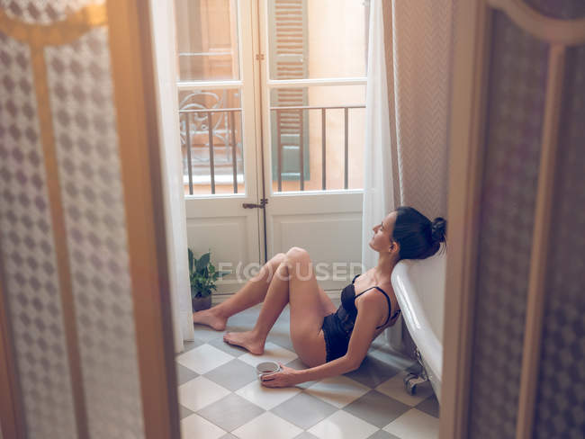 Femme assise et relaxante à la fenêtre — Photo de stock
