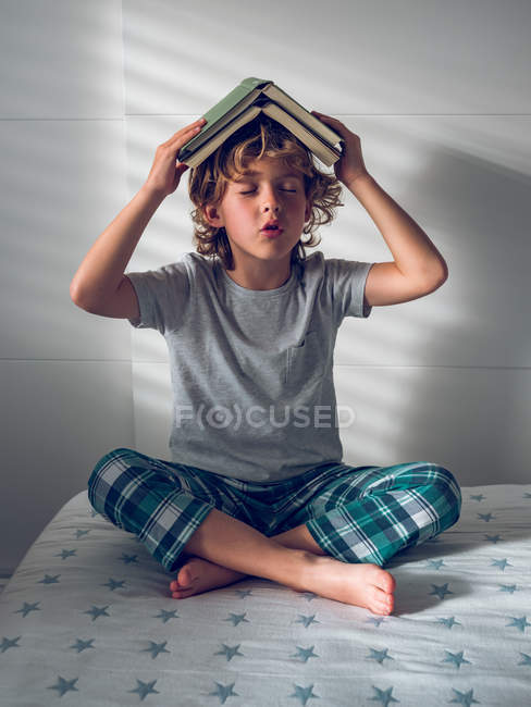 Хлопчик з книгами над головою — стокове фото