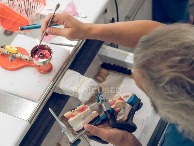 Hombre de las cosechas aplicando sustancia a la prótesis dental - foto de stock