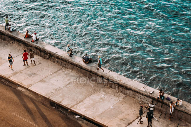 LA HABANA, CUBA - 1er MAI 2018 : les gens se reposent sur le front de mer pavé avec de l'eau courante, Cuba — Photo de stock