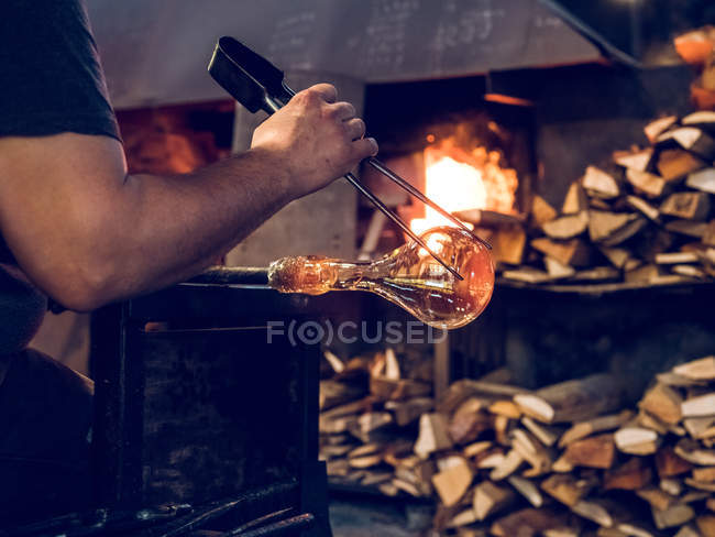 Craftsman putting pipe with glass in burning industrial furnace on factory. — Stock Photo