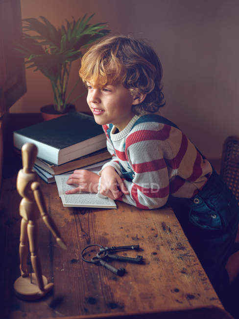 Junge sitzt mit Buch am Tisch — Stockfoto
