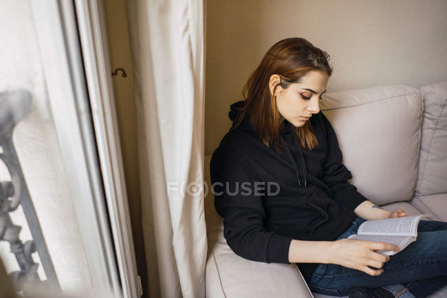 Женщина расслабляется с книгой на дому — стоковое фото