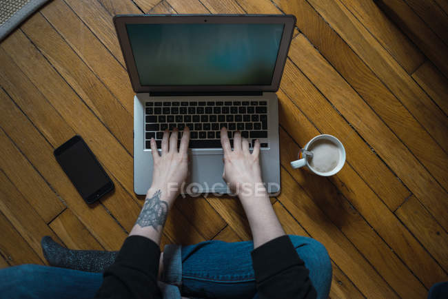 Mains féminines tapant sur ordinateur portable sur le sol — Photo de stock