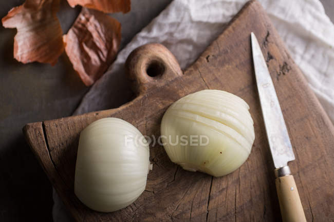 Cebolla fresca parcialmente picada sobre tabla de cortar de madera - foto de stock