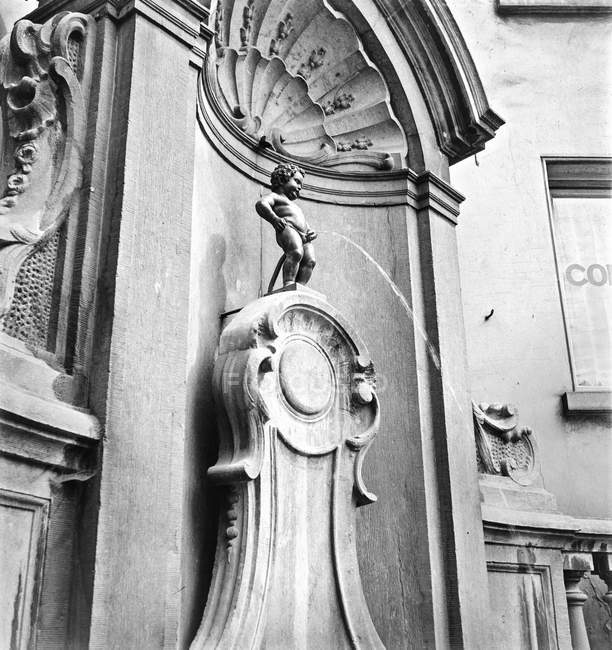 Schwarz-Weiß-Aufnahme pinkelnder Knabe Skulptur auf Steinelement des Brunnens, Belgien. — Stockfoto