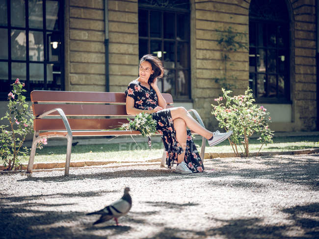 Woman with bunch of flowers on bench — Stock Photo