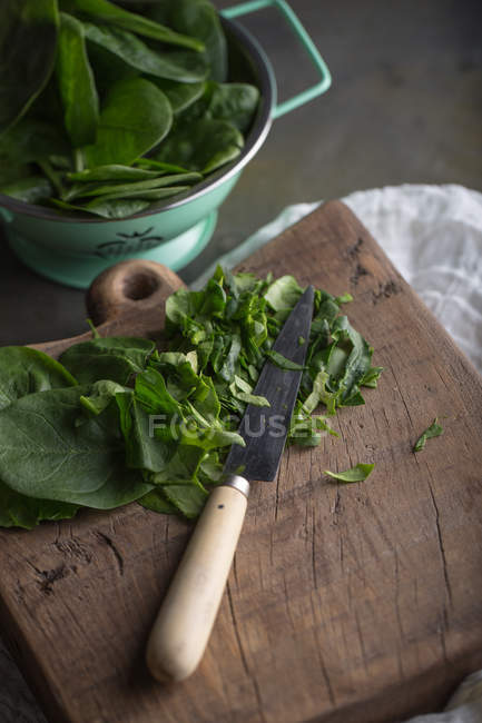 Частково подрібнене зелене листя шпинату на дерев'яній дошці — стокове фото