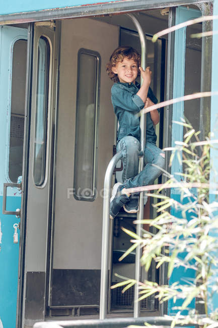 Niño sentado en barandilla de tren - foto de stock