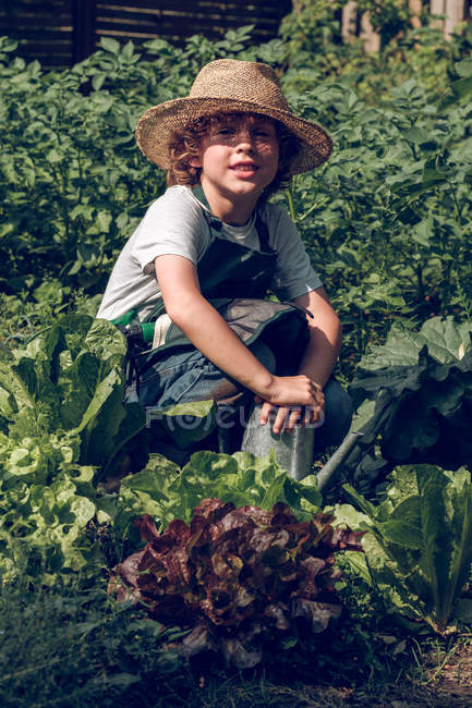 Niño agachado en el jardín - foto de stock