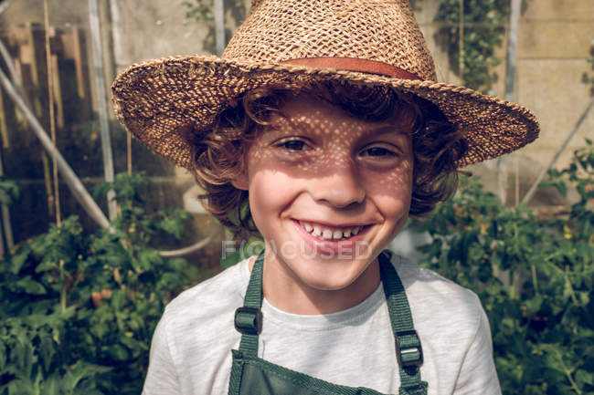 Мальчик в соломенной шляпе с вьющимися волосами — стоковое фото