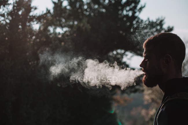 Bärtiger Mann raucht im Wald — Stockfoto