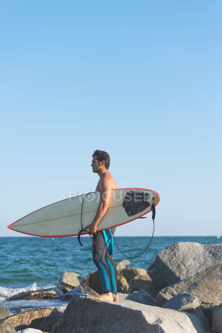 Mann mit Surfbrett steht an Küste — Stockfoto
