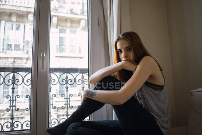 Femme tatouée assise à la fenêtre — Photo de stock