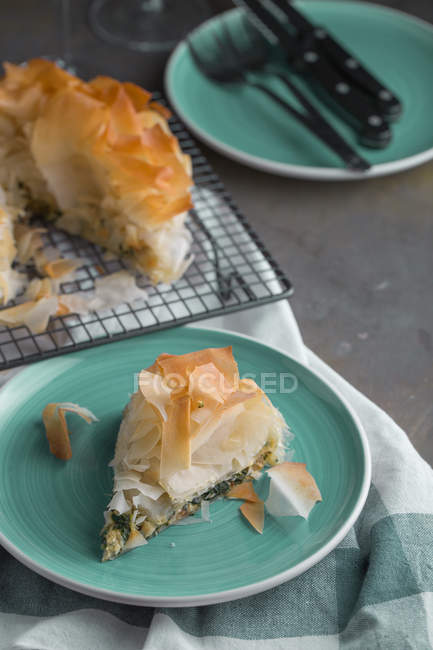 Pedazo de pastel tradicional de espinacas griegas spanakopita en plato azul - foto de stock