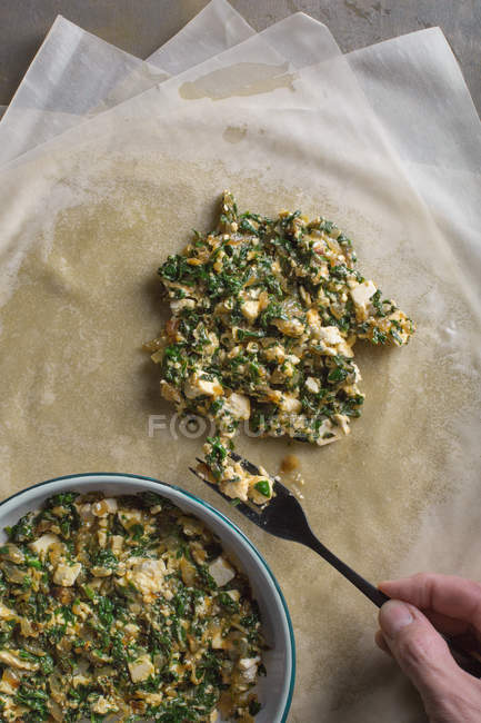 Human hand preparing stuffing for traditional spanakopita spinach pie — Stock Photo