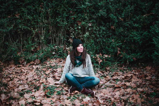 Woman sitting on autumn foliage — Stock Photo