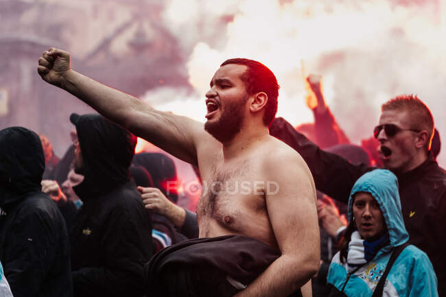 Homem sem camisa gritando em grupo de fãs — Fotografia de Stock