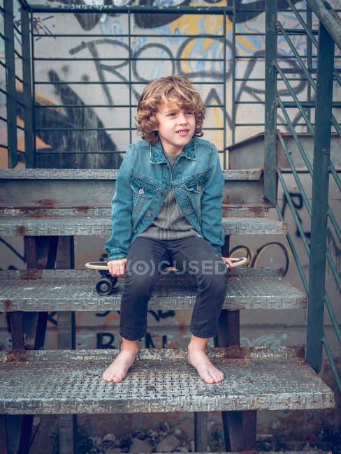 Босоногий мальчик стоит на лестнице — стоковое фото