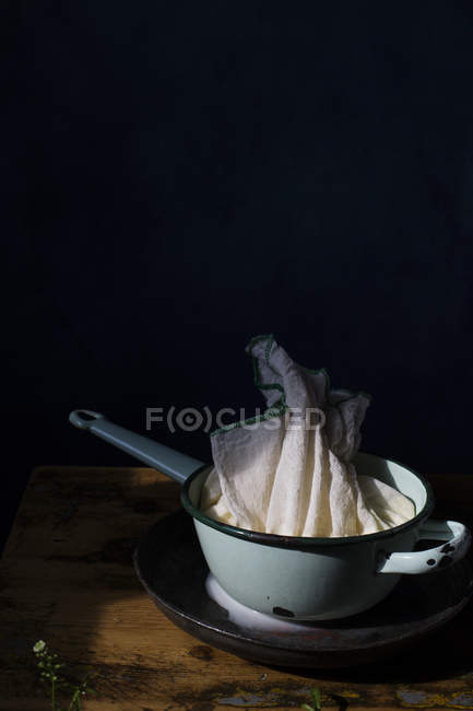 Pentola con preparato per spremere fiocchi di latte sul tavolo . — Foto stock
