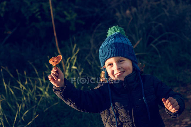 Усміхнений хлопчик показує гриб — стокове фото