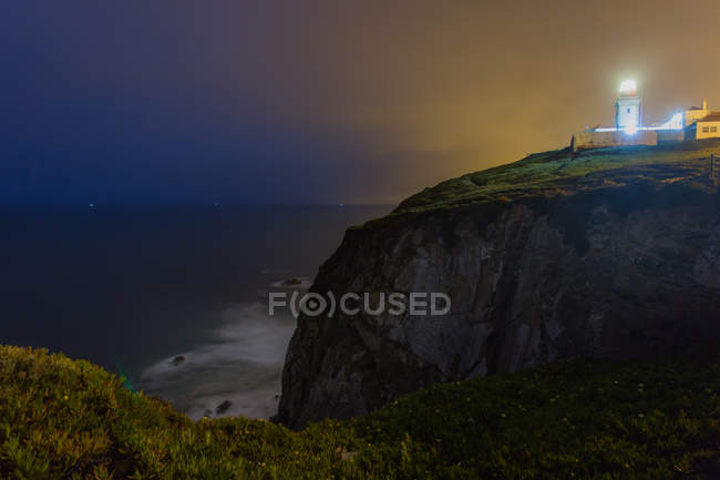 Освещенный маяк ночью — стоковое фото