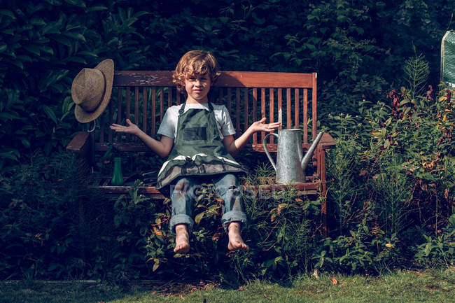 Niño sentado en el banco - foto de stock