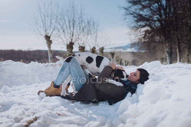 Mulher brincando com cão no inverno — Fotografia de Stock